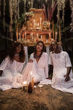 three women sitting on the ground with candles in front of them