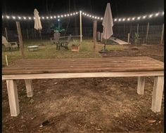 a wooden bench sitting in the middle of a yard with lights on it's sides