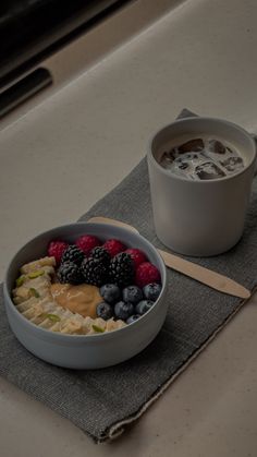 a bowl of fruit and yogurt on a napkin next to a cup of coffee