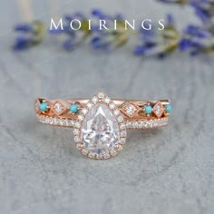 an engagement ring with a pear shaped diamond in the center and turquoise stones on each band