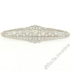 "Here we have a stunning diamond brooch crafted in solid platinum during the art deco period. It features 7 large old European cut diamonds which are bead set in elegantly milgrain-etched octagonal shape baskets. The brooch is then drenched with petite old mine cut diamonds which total approximately 1.20 carats, beautifully accenting this piece along with the finest etching work and filigree designs showcasing the masterful workmanship used during the art deco period. The center diamond is a lar Vintage Platinum Brooches With Diamond Accents, Classic Platinum Brooches, Vintage Platinum White Gold Brooches, Vintage Platinum Brooch In White Gold, Vintage White Gold Platinum Brooches, Classic Platinum Brooches With Diamond Accents, Classic Platinum Brooch For Anniversary, Classic Platinum Brooches For Anniversary, Classic Diamond White Diamond Brooch