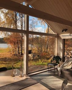 a screened porch with chairs and tables on the side, looking out onto a lake