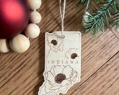 a wooden ornament with the state of indiana on it next to christmas ornaments