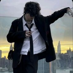 a man in a suit and tie standing on top of a building looking at his cell phone