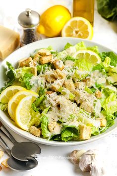 a salad with lemons, chicken and parmesan cheese in a white bowl