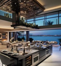 an open kitchen and dining area with large windows overlooking the water at night, is shown in this modern home