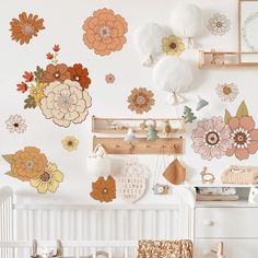 a white crib with lots of flowers on the wall and hanging decorations above it