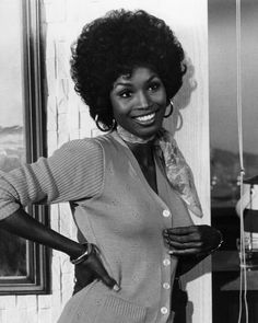 an old black and white photo of a woman with curly hair wearing a cardigan