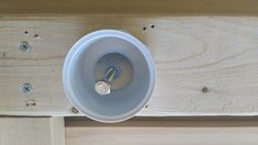 a white light fixture mounted on the side of a wooden wall next to screws