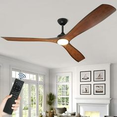 a person holding a remote control up to a ceiling fan