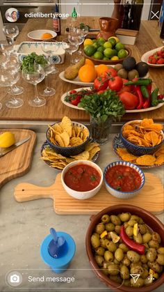 the table is full of different types of food, including olives, tomatoes and chips