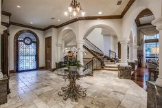 a foyer with marble flooring and chandelier in the center is surrounded by arched doorways