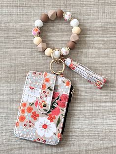 a flowered wallet with a tassel hanging from it's front and side