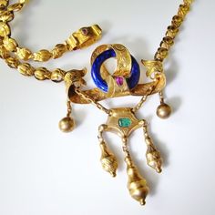 A museum quality hand crafted 1870s necklace in luxurious solid 14K yellow gold decorated with fine hand guilloche enamel work and set with a natural emerald and earth mined fine rubies. This one of a kind exceptional necklace has strong arts and craft movement influences. In the 1870s there was a reaction away from machine production and mass production of all items. Craftsman wanted to reproduce the hand made goods of earlier periods. They were strongly influenced by the ideal of the medieval Ornate Jewel Pendant Necklace, Victorian Yellow Gold Cabochon Jewelry, Ornate Pendant Necklace With Jewels, Antique Cabochon Jewelry For Ceremonial Occasions, Antique Yellow Gold Jeweled Necklaces, Victorian Cabochon Ceremonial Jewelry, Victorian Enamel Jewelry For Ceremonial Occasions, Victorian Hallmarked Necklaces For Ceremonial Occasions, Victorian Hallmarked Necklaces For Ceremonial Events