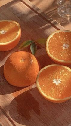 four oranges sitting on top of a wooden table