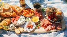 a platter filled with bread, meats and veggies on a blanket