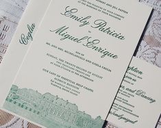 two green and white wedding cards sitting on top of a lace covered table cloth,