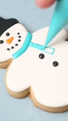 a cookie decorated like a snowman being frosted