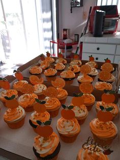 cupcakes with orange frosting are arranged on a table