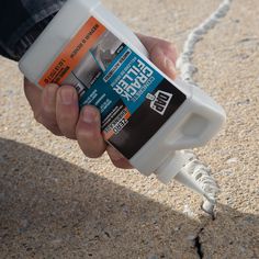 a person holding a bottle of glue in their left hand while standing on the ground