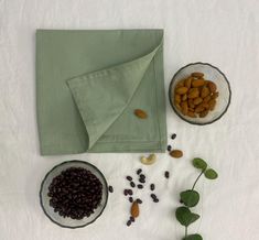 nuts, raisins, and green napkin on a white tablecloth next to bowls of food