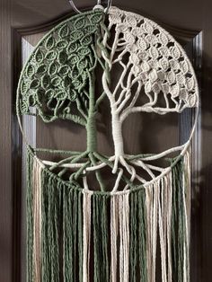 a green and white crocheted tree of life dream catcher hanging on a door