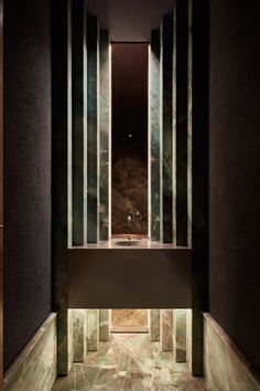 a bathroom with marble walls and flooring in the shower area is lit by recessed lighting