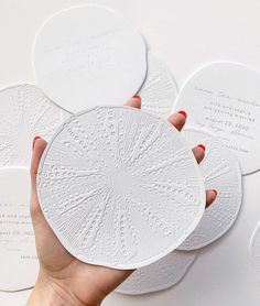 a person holding four white coasters in their hand