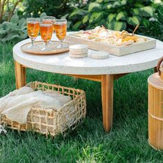 an outdoor table with drinks and snacks on it, in the middle of some grass