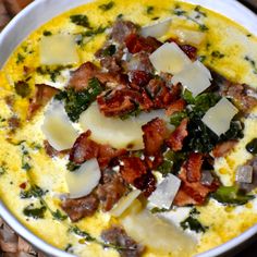 an omelet with bacon, cheese and spinach in a white bowl on a wicker place mat