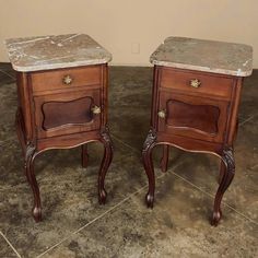 two wooden nightstands with marble top sitting side by side on the floor in front of a wall