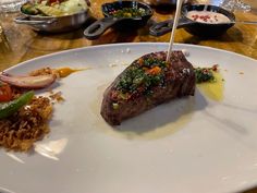 a white plate topped with meat and veggies on top of a wooden table