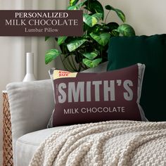 a pillow that says smith's milk chocolate sitting on a couch next to a potted plant