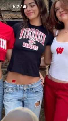 three girls standing next to each other in front of a brick wall with the word wisconsin on it