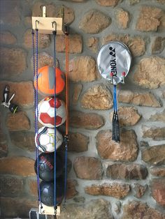 there is a racket and some balls hanging on the wall next to a stone wall