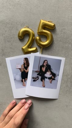 someone holding up two photos with the number twenty five on them and one has a golden balloon