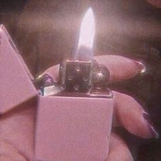 a person holding a pink lighter in their right hand and the lighter is lit up