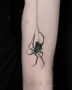 a black and white tattoo of a spider on the right arm, with its web attached to it