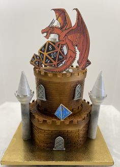 a cake made to look like a castle with a red dragon on top and blue diamond