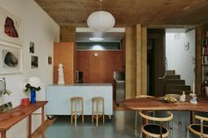 an open kitchen and dining area with wooden tables, stools and bookshelves