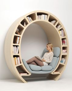 a woman sitting in a circular chair with bookshelves on the sides and she is reading