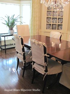 a dining room table with white chairs and a chandelier hanging from the ceiling