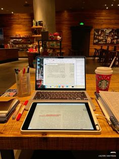 an open laptop computer sitting on top of a wooden table next to a cup of coffee