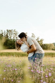 a man and woman kissing in a field full of flowers