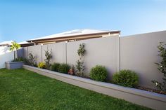 a fenced in backyard with grass and plants