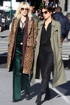 two women walking down the street together wearing coats and pants with leopard print on them