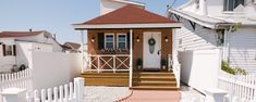 a small brick house with white picket fence and steps leading up to the front door