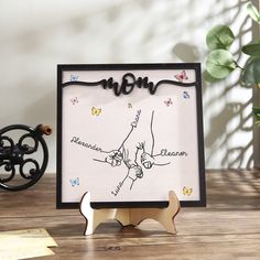 a wooden frame with a hand holding the word mom on it and butterflies around it