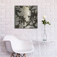 a white chair sitting in front of a table with a vase on top of it