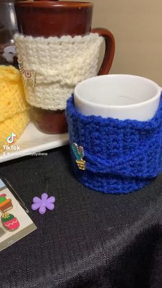 three knitted coffee cups sitting on top of a table next to a cup holder